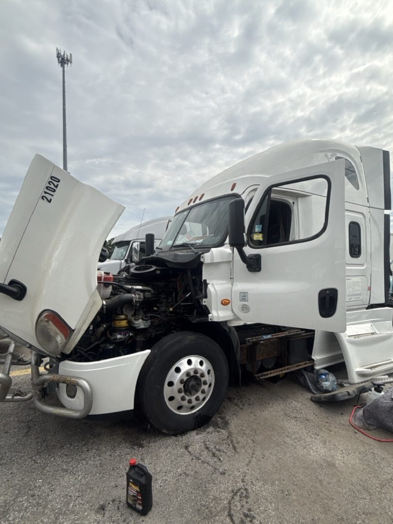 White Freightliner Cascadia with hood open in truck stop lot