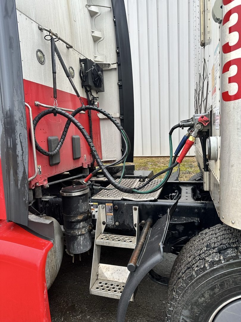 Red and white Peterbilt cab with air lines being serviced